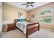 Cozy bedroom featuring a ceiling fan, a wood sleigh bed, and a window offering natural light at 19708 Wellington Manor Blvd, Lutz, FL 33549