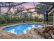 Relaxing pool area with lounge chairs, an umbrella, a covered lanai, and mature landscaping at 19708 Wellington Manor Blvd, Lutz, FL 33549