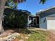 Charming single-story home featuring a quaint entryway, attached garage, and a vibrant front yard landscape at 2342 Carrie Ct, Dunedin, FL 34698