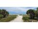 A serene view of a sandy path leading to a beautiful beach with clear blue water at 250 Aberdeen St, Dunedin, FL 34698