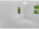 Bright bedroom features white walls, tiled floor, ceiling fan, and windows overlooking lush greenery at 250 Aberdeen St, Dunedin, FL 34698