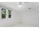 White bedroom with a ceiling fan, closet, and windows showing outside at 250 Aberdeen St, Dunedin, FL 34698