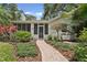 Inviting home entrance with a brick path leading to a screened-in porch, surrounded by landscaped greenery at 250 Aberdeen St, Dunedin, FL 34698