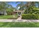Charming home showcasing a lush landscaped front yard with a brick walkway and mature trees at 250 Aberdeen St, Dunedin, FL 34698