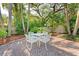 Charming brick patio features a dining set nestled within a lush, landscaped backyard at 250 Aberdeen St, Dunedin, FL 34698