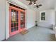 Inviting screened porch featuring a tile floor, ceiling fans, and vibrant coral-colored doors, creating a cozy outdoor living space at 250 Aberdeen St, Dunedin, FL 34698