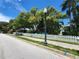 Street view of quaint white picket fence with mature trees and blue sky overhead at 250 Aberdeen St, Dunedin, FL 34698