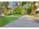 A scenic view showcasing a paved driveway, verdant lawn, and lush landscaping leading up to the charming home at 250 Aberdeen St, Dunedin, FL 34698