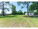 Spacious backyard with a lush green lawn, mature trees, and a large metal garage, perfect for outdoor activities at 3319 Fox Ridge Blvd, Wesley Chapel, FL 33543