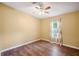 This bedroom has a ceiling fan, wood floors, a window with light curtains and yellow walls at 3319 Fox Ridge Blvd, Wesley Chapel, FL 33543
