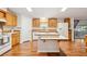Well-lit kitchen featuring wood cabinetry, a kitchen island, tile backsplash, and bright countertops at 3319 Fox Ridge Blvd, Wesley Chapel, FL 33543