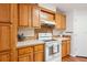 Kitchen with wood cabinetry, white countertops, tiled backsplash, and a white range oven with a hood at 3319 Fox Ridge Blvd, Wesley Chapel, FL 33543