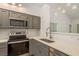 Modern kitchen with stainless steel appliances, gray cabinets, quartz countertops, and stylish lighting fixtures at 3583 Wembley Way # 101, Palm Harbor, FL 34685