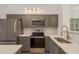 Updated kitchen with stainless steel appliances, modern gray cabinetry, quartz countertops, and recessed lighting at 3583 Wembley Way # 101, Palm Harbor, FL 34685
