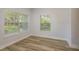 Inviting living room with wood-look flooring, white walls, two windows with views, and neutral decor at 3583 Wembley Way # 101, Palm Harbor, FL 34685