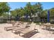 Relaxing pool deck area featuring comfortable lounge chairs and tables under shade umbrellas at 3583 Wembley Way # 101, Palm Harbor, FL 34685
