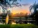 Stunning view of a pond at sunset with a fountain, reflecting the vibrant colors of the sky and surrounding trees at 3611 Pine Knot Dr, Valrico, FL 33596