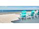 Teal and white adirondack chairs offer a relaxing view of the ocean and sandy beach at 4256 Rudder Way, New Port Richey, FL 34652