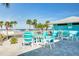 Inviting outdoor patio with turquoise tables and chairs, surrounded by lush palm trees and clear blue skies by the beach at 4256 Rudder Way, New Port Richey, FL 34652