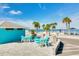 Inviting outdoor patio with turquoise tables and chairs, surrounded by palm trees and clear blue skies near the sandy beach at 4256 Rudder Way, New Port Richey, FL 34652