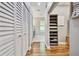 Well-lit hallway with wood flooring, white closet doors, and convenient shelving storage at 5416 Twin Creeks Dr, Valrico, FL 33596