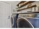 Modern laundry room with front-loading washer and dryer, custom shelving, and stylish decor at 5416 Twin Creeks Dr, Valrico, FL 33596