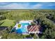 Aerial view of a community pool with a clubhouse, playground, and sports field at 5902 War Admiral Dr, Wesley Chapel, FL 33544