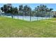Outdoor tennis court surrounded by green grass and mature trees, perfect for recreational activities at 719 Pinellas Bayway S # 309, Tierra Verde, FL 33715