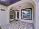 Covered front porch with stone floors and windows with views to the front yard at 7609 Barry Rd, Tampa, FL 33615