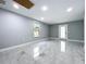 Open living room features gray walls, tile floors, a window, and a door to the outside at 7609 Barry Rd, Tampa, FL 33615