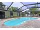 Backyard view of the bright blue kidney-shaped swimming pool inside of a screened in enclosure at 7609 Barry Rd, Tampa, FL 33615