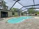 Backyard view of the bright blue kidney-shaped swimming pool inside of a screened in enclosure at 7609 Barry Rd, Tampa, FL 33615