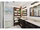 Bright bathroom featuring double sinks, a wooden shelving unit, and tiled floors for a classic look at 811 E Flora St, Tampa, FL 33604
