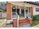 Charming front porch with brick stairs and columns, with hanging plants and a colorful rug at 811 E Flora St, Tampa, FL 33604