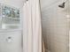 Bright shower area features white tile, shower curtain, and window with view at 811 E Flora St, Tampa, FL 33604