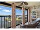 Enclosed condo balcony with water view features wicker furniture, ceiling fan, and decorative curtains at 8141 Aquila St # 346, Port Richey, FL 34668