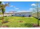 View of the home's exterior from the back yard with a lush lawn and an open garden area at 8919 Drummer Plank Dr, Wesley Chapel, FL 33545