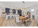 Open dining and kitchen area with wood table and seating plus modern chandelier and open view of stainless appliances at 8919 Drummer Plank Dr, Wesley Chapel, FL 33545