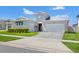 Charming single-story home featuring a well-manicured lawn, a brick driveway, and a stylish blue front door at 8919 Drummer Plank Dr, Wesley Chapel, FL 33545