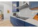 Modern kitchen featuring sleek navy cabinets, white countertops, tile backsplash and stainless steel appliances at 8919 Drummer Plank Dr, Wesley Chapel, FL 33545