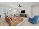 Open-concept living room with a leather sectional, modern media cabinet, and large windows for natural light at 8919 Drummer Plank Dr, Wesley Chapel, FL 33545