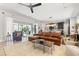 Spacious living room featuring a leather sectional, modern fan, and sliding glass doors to the outdoor area at 8919 Drummer Plank Dr, Wesley Chapel, FL 33545