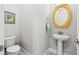 Cozy powder room featuring a pedestal sink, round mirror, and a two-piece toilet at 8919 Drummer Plank Dr, Wesley Chapel, FL 33545