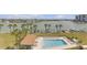 Aerial view of community pool, featuring palm trees, lounge chairs, boat docks, and waterway views at 9815 Harrell Ave # 502, Treasure Island, FL 33706