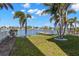 Spacious backyard featuring lush greenery, mature palm trees, and a private dock on the water at 10110 Yacht Club Dr, Treasure Island, FL 33706