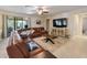 Comfortable living room with tile floors, fan, and a large leather sectional sofa with a door to the back porch at 10404 Scarlet Chase Dr, Riverview, FL 33569