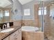 Relaxing bathroom features a soaking tub, walk-in shower, granite vanity and neutral tile surround at 10501 Dotham Ct, Tampa, FL 33626