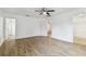 Spacious bedroom featuring wood-look flooring, a ceiling fan, and ample natural light from nearby doors and windows at 10603 Massimo Dr, Wimauma, FL 33598