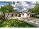 Inviting single-story home with lush green lawn, mature landscaping, and a welcoming front entrance at 10609 Orange Grove Dr, Tampa, FL 33618
