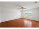 Bright bedroom featuring hardwood floors, a ceiling fan, and a window overlooking the yard at 13420 Copper Head Dr, Riverview, FL 33569